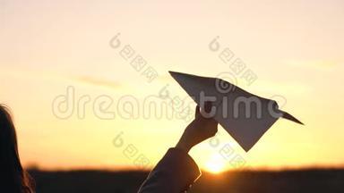 女人在日落的背景下发射纸飞机。 想去度假或旅行的概念。 慢动作